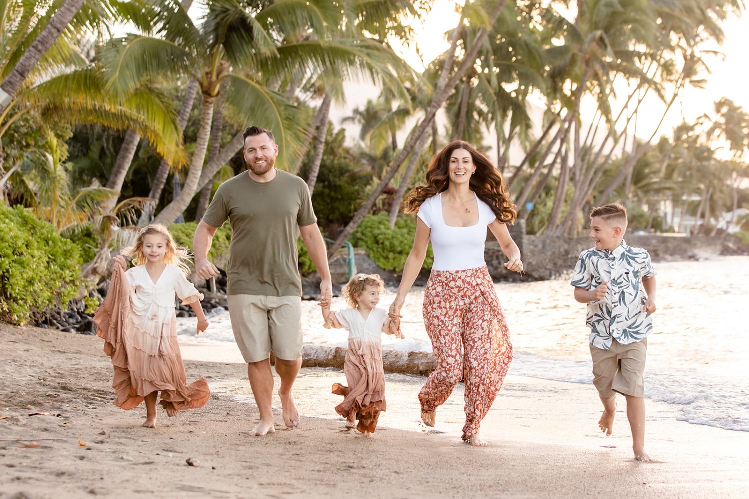 Family of five joyfully walking on a tropical beach at sunset.